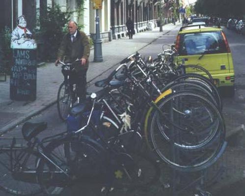 Amsterdam, Nl. :: Note the bike path protected from the street by parked cars. The parked bikes are protected by the metal bumpers on the right. This rack can be quickly removed from the street.