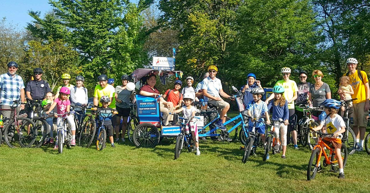 Contact CentreBike for more information on activities and events like this group ride with people posing with bikes and a rickshaw in a grassy hillside.